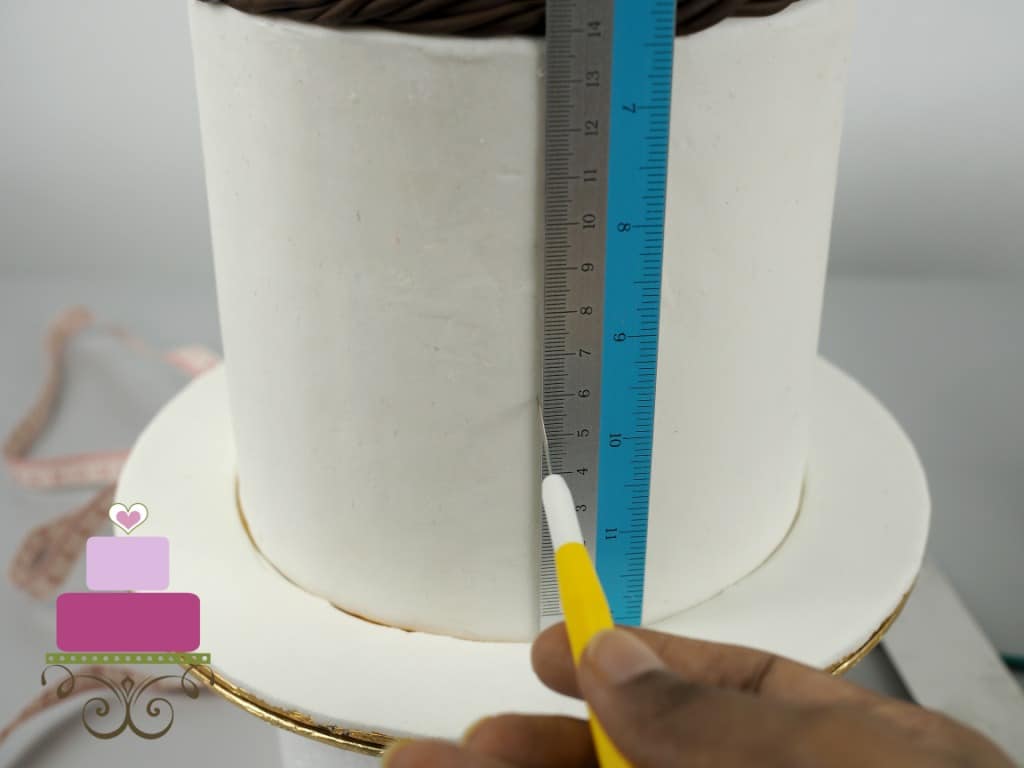 Using a needle tool and a ruler to mark a cake