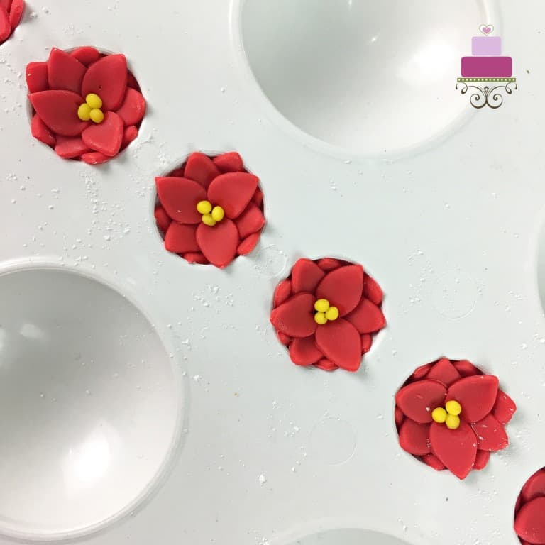 Tiny red fondant poinsettia flowers in a flower former.