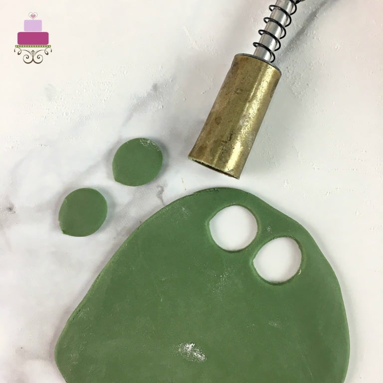 Using an oval plunger cutter to cut out rolled green fondant.