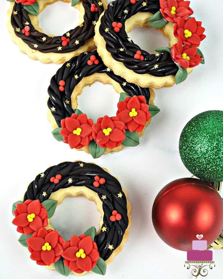 Christmas wreath cookies decorated to look like poinsettia wreaths.