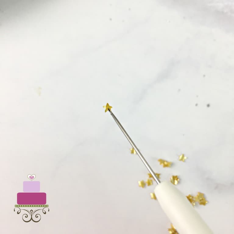 A tiny sugar star lifted with the tip of a needle tool.