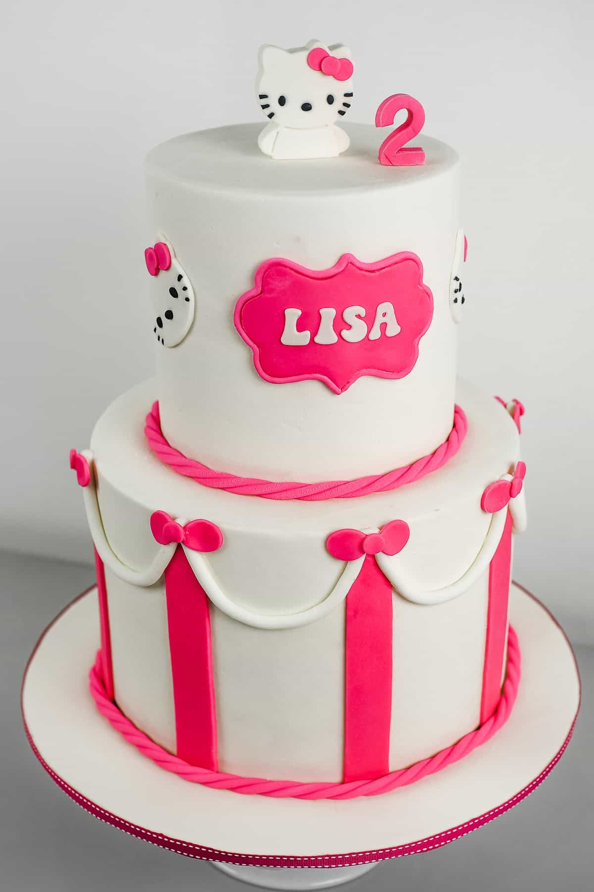 A white and pink 2 tier Hello Kitty Birthday cake