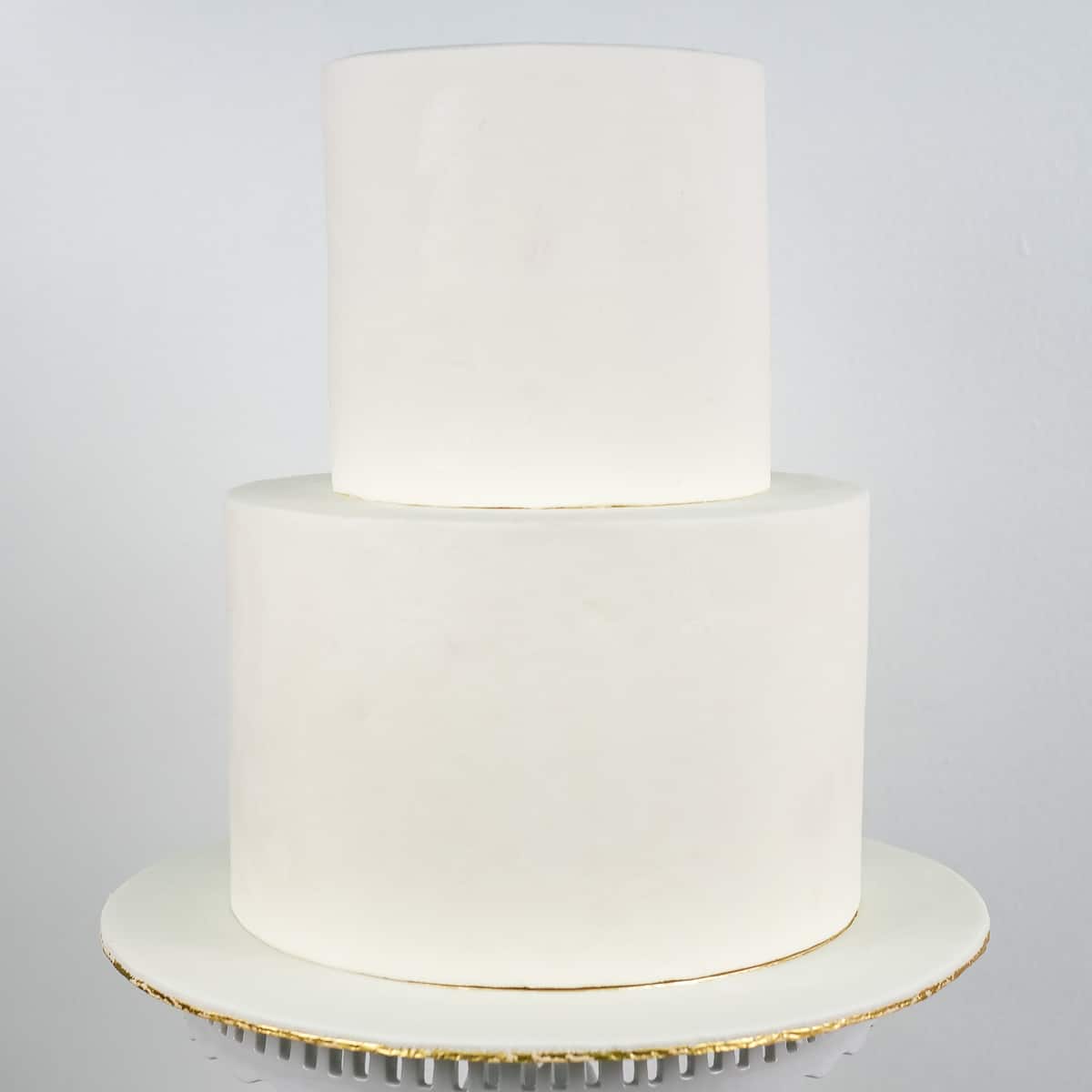 A 2 tier cake covered in white fondant