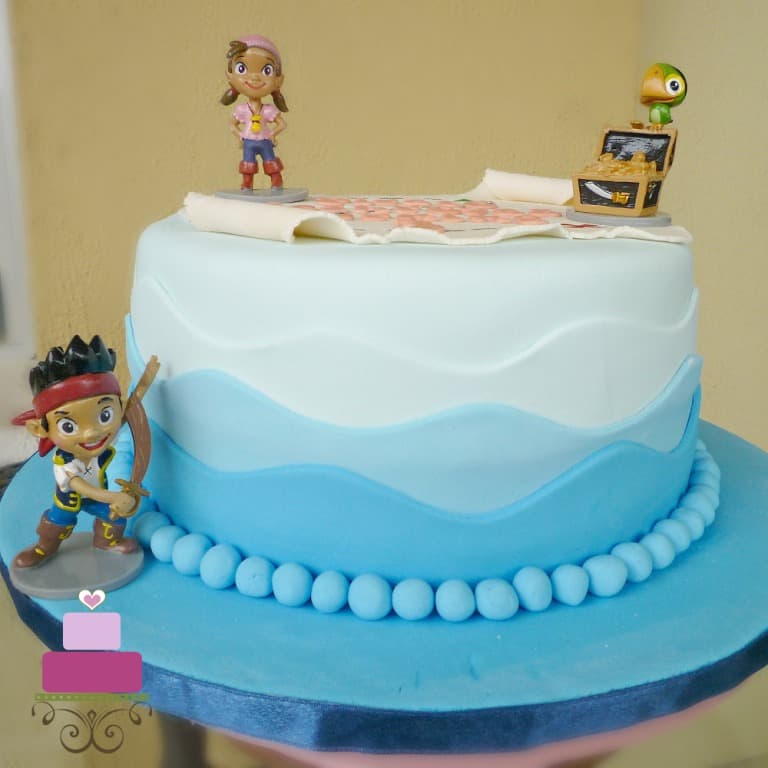 A round cake with a fondant pirate map and Jake and the Neverland Pirates toy toppers