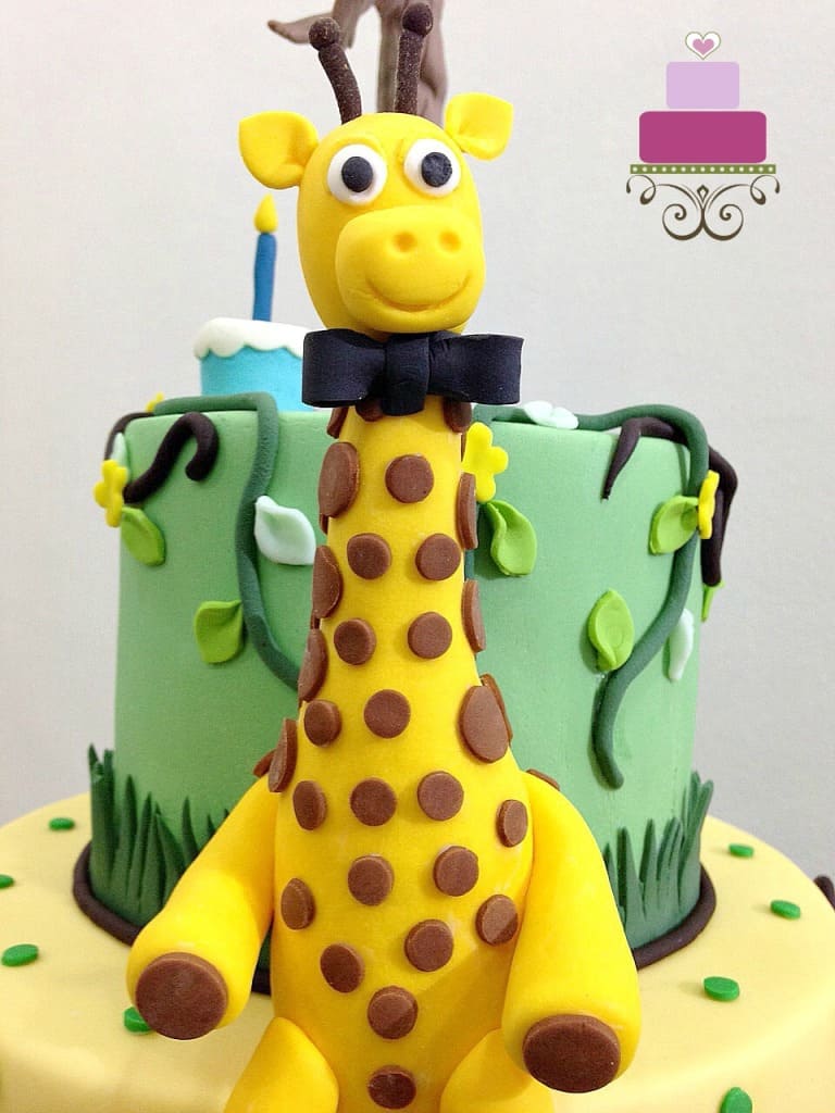 3D fondant giraffe with a bow, sitting on a cake