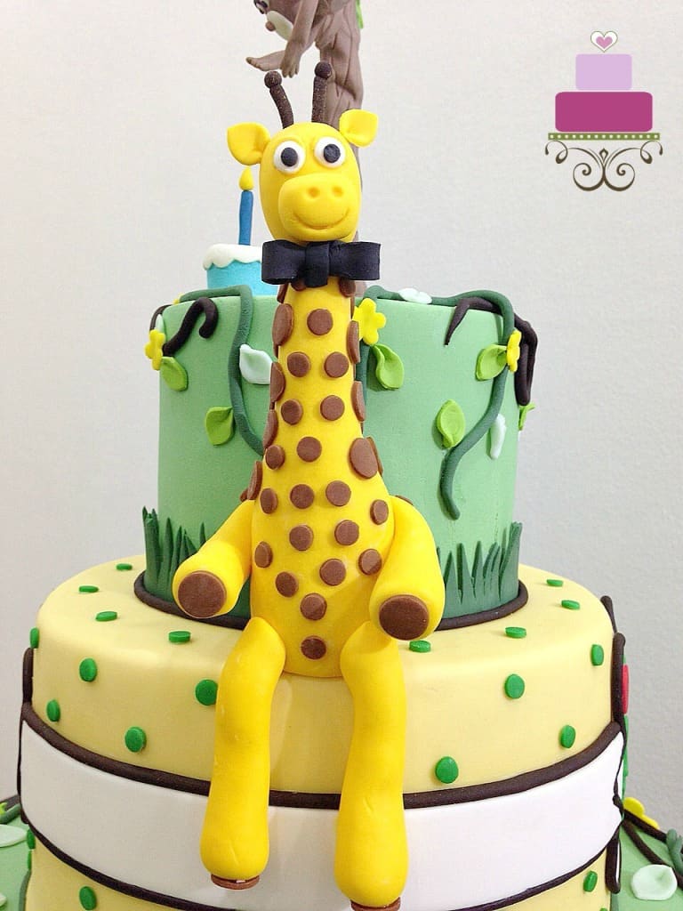 3D fondant giraffe with a bow, sitting on a cake