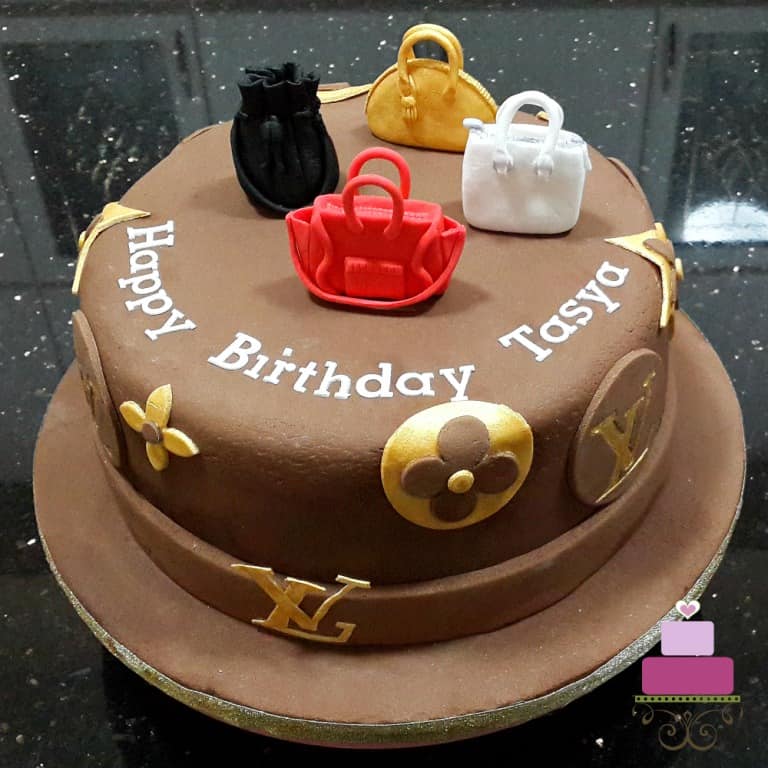 A round cake covered in chocolate fondant and decorated with LV monogram and 4 handbag toppers