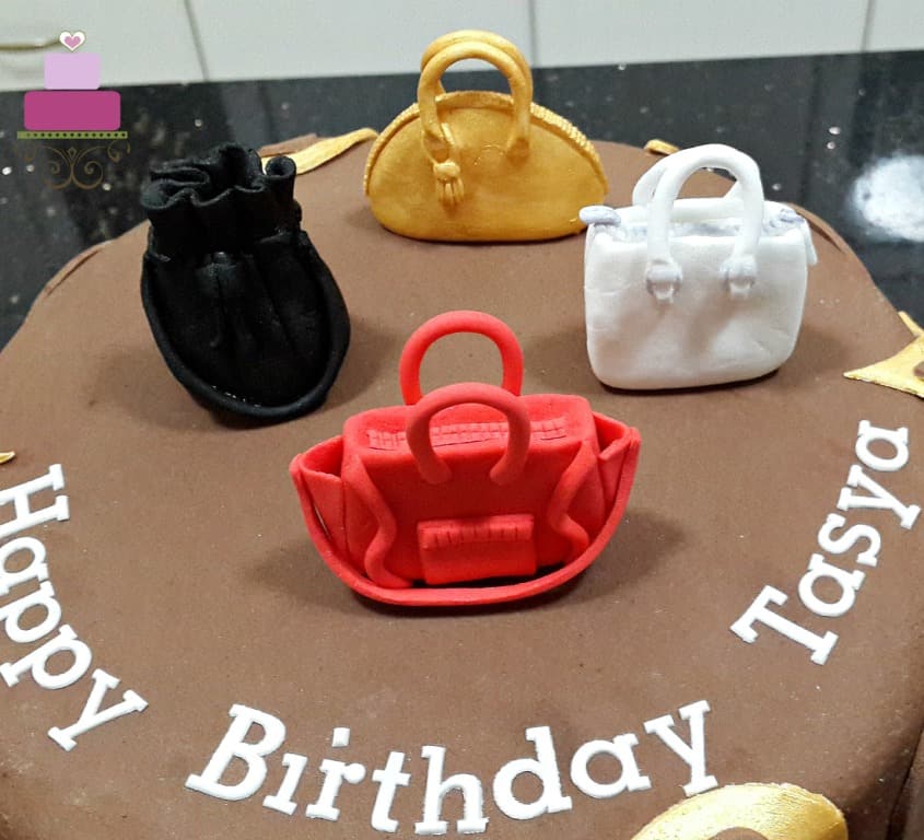 Fondant handbag toppers in red, white, black and gold on a brown Louis Vuitton cake