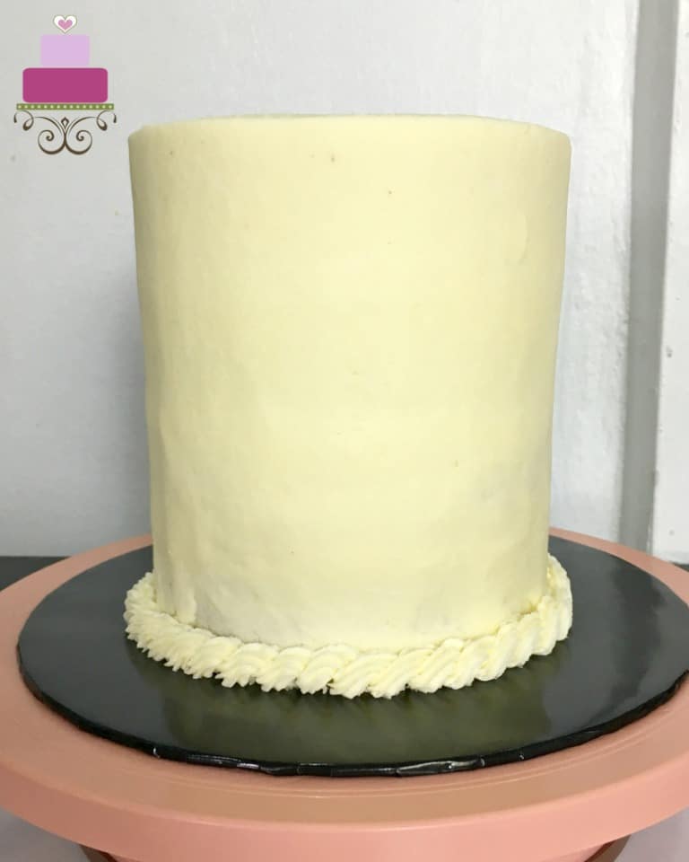 A plain buttercream covered cake with a simple rope border