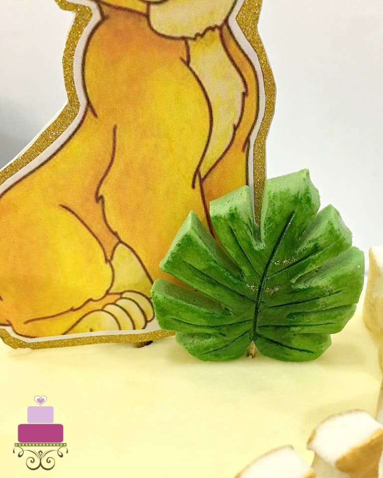 A green fondant leaf on top of a cake