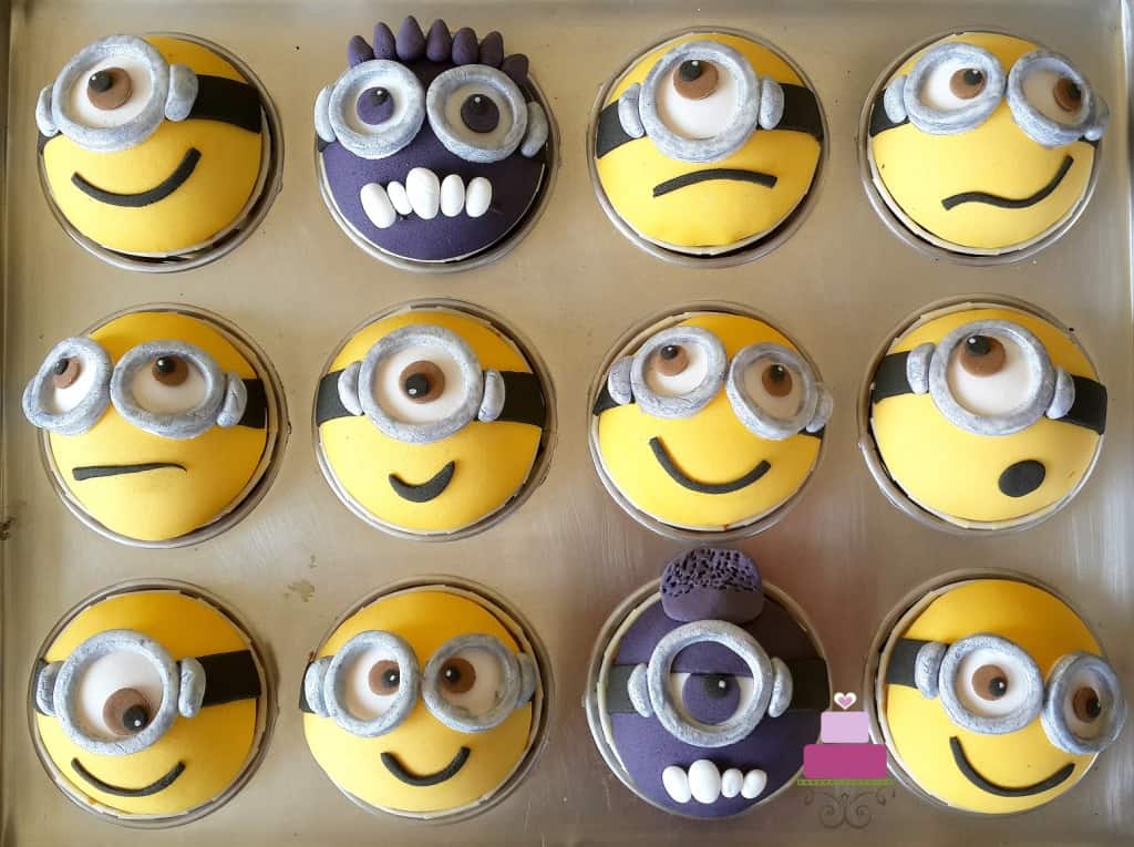 Minion cupcakes decorated with various yellow and purple minion faces