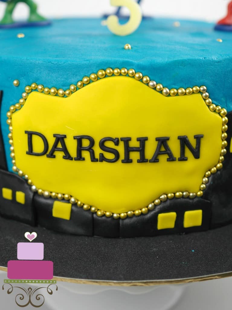 Yellow fondant plaque with wordings Darshan in black. Plaque is framed with gold beads
