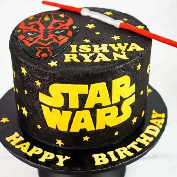 A round black cake with Star Wars themed cake.