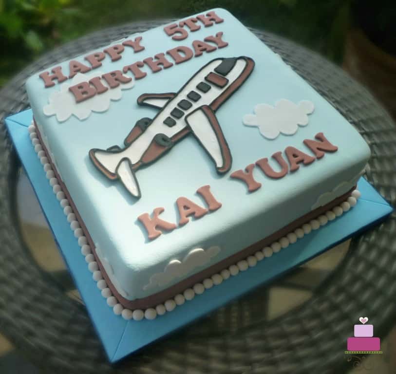 A square cake with an airplane motif on it.