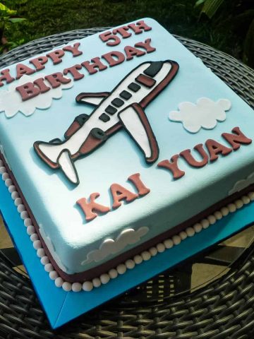 A square cake with an airplane motif on it.