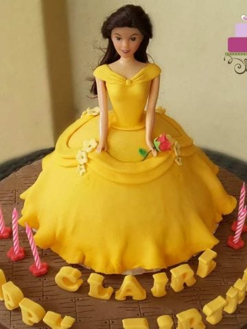 A doll cake decorated in yellow gown and a stalk of rose like Belle from Beauty and the Beast