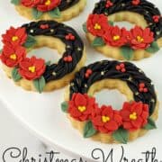 Ring shaped cookies decorated with fondant wreath and poinsettia flowers in a plate.