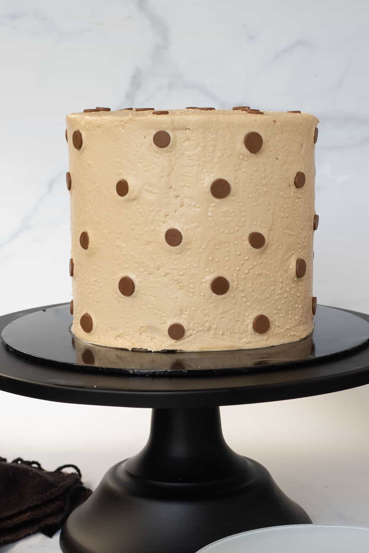 A round cake on a black cake stand.