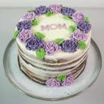 A round cake decorated with purple and violet roses.