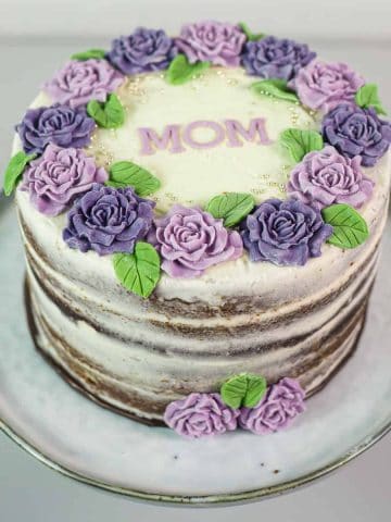 A round cake decorated with purple and violet roses