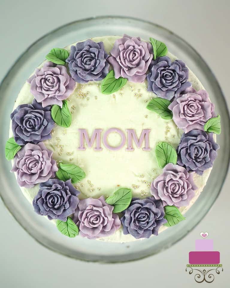 A round cake decorated with purple and violet roses