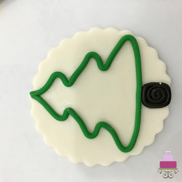 A round piece of fondant decorated with a Christmas tree motif