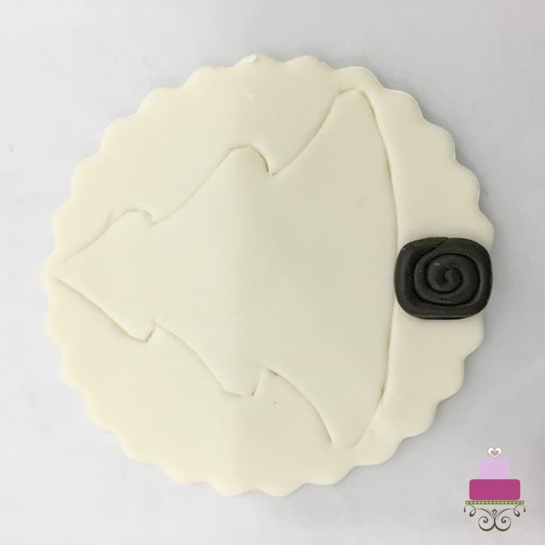 A round piece of fondant decorated with a Christmas tree motif