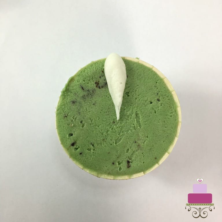 A white buttercream petal on a green cupcake.