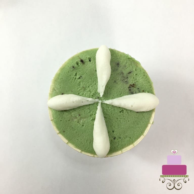 4 white petals on a green buttercream covered cupcake.