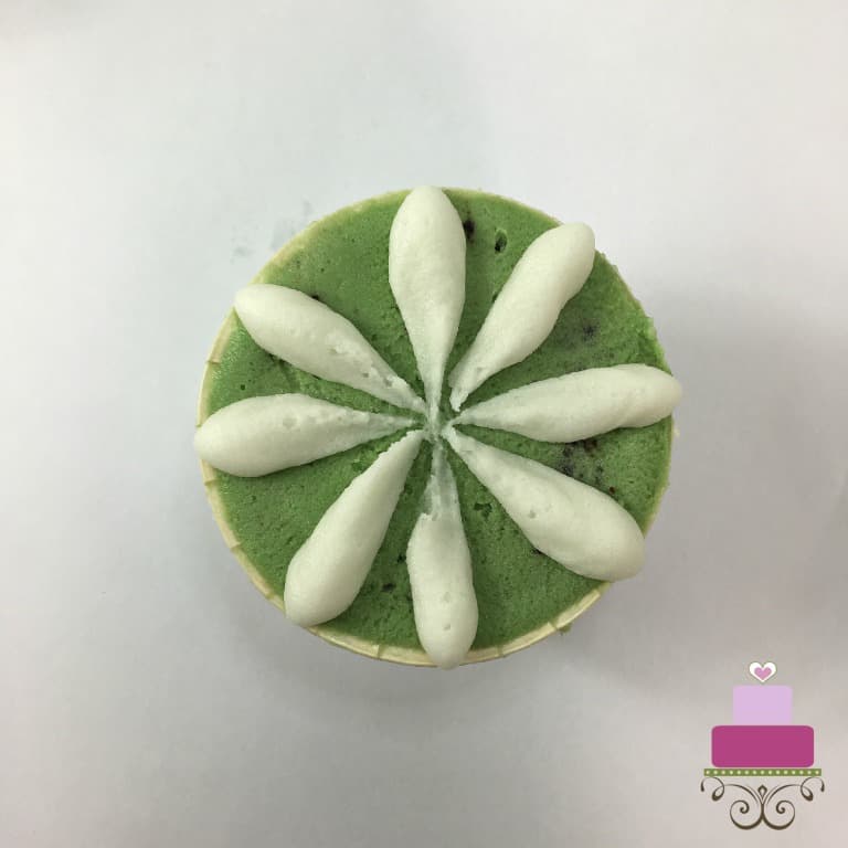 White petals on a green buttercream covered cupcake.