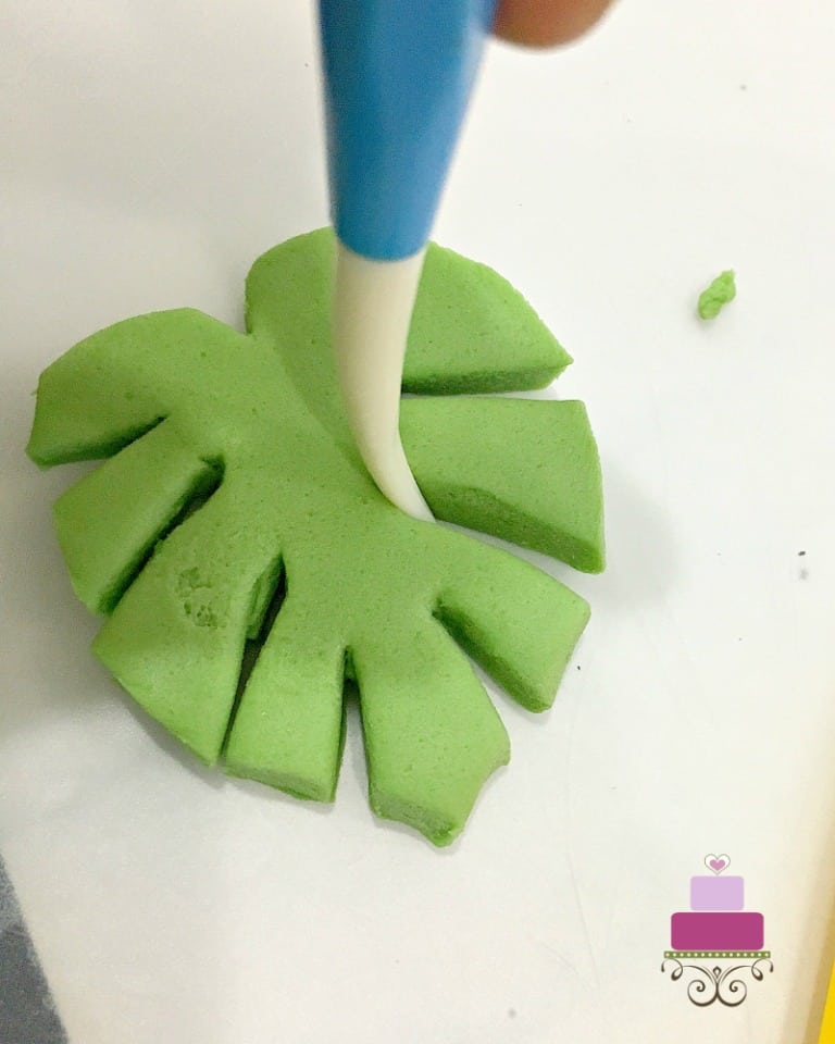 Shaping a fondant palm leaf with a fondant tool