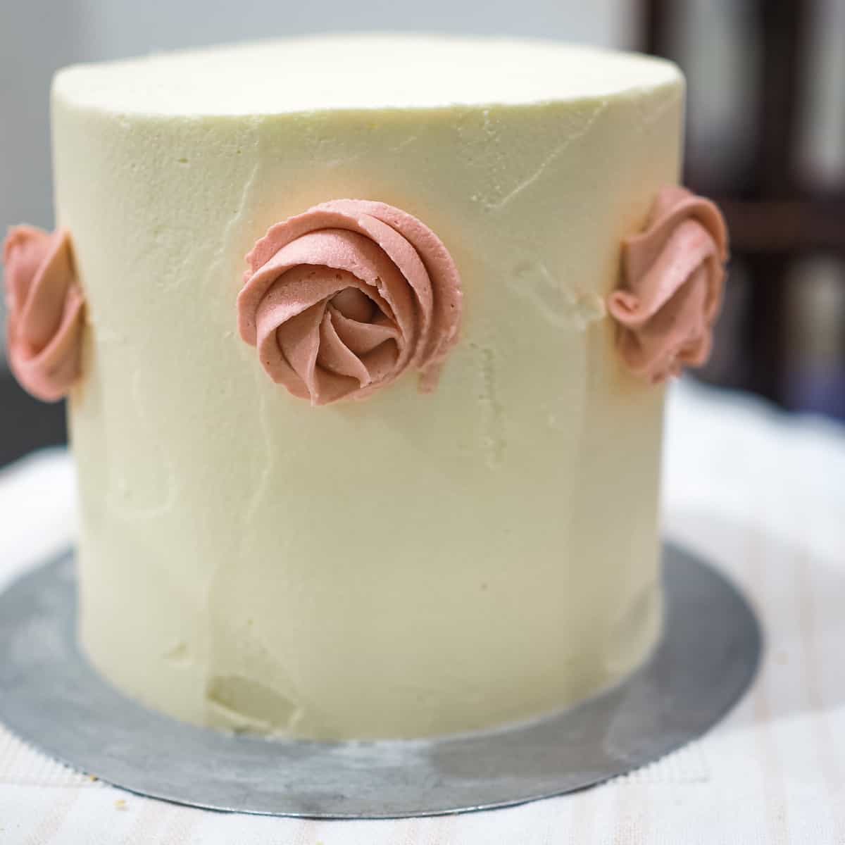 Pink buttercream roses on the side of a cake