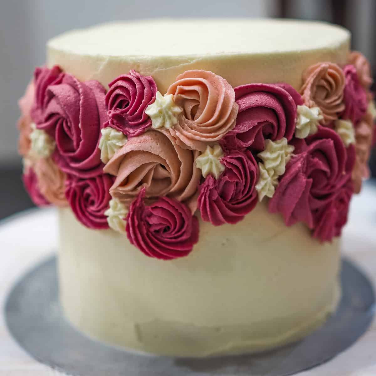 A round cake with buttercream flowers on the sides