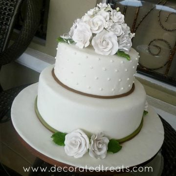 A 2 tier cake in white fondant and matching white roses