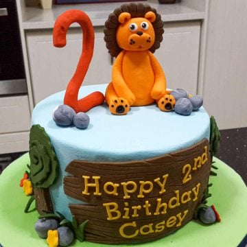 A round cake with a lion and number 2 cake topper.