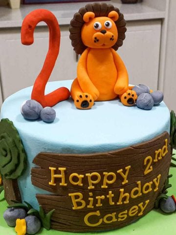 A round cake with a lion and number 2 cake topper.