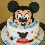 A round cake with 3D Mickey face as the top tier.