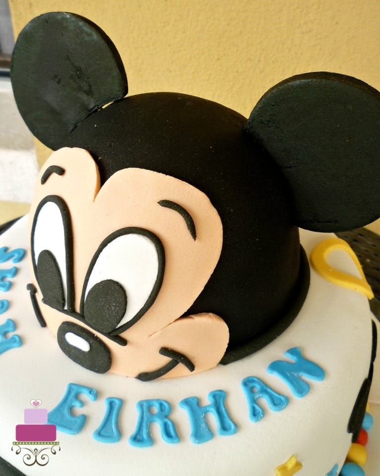 A round cake with 3D Mickey face as the top tier