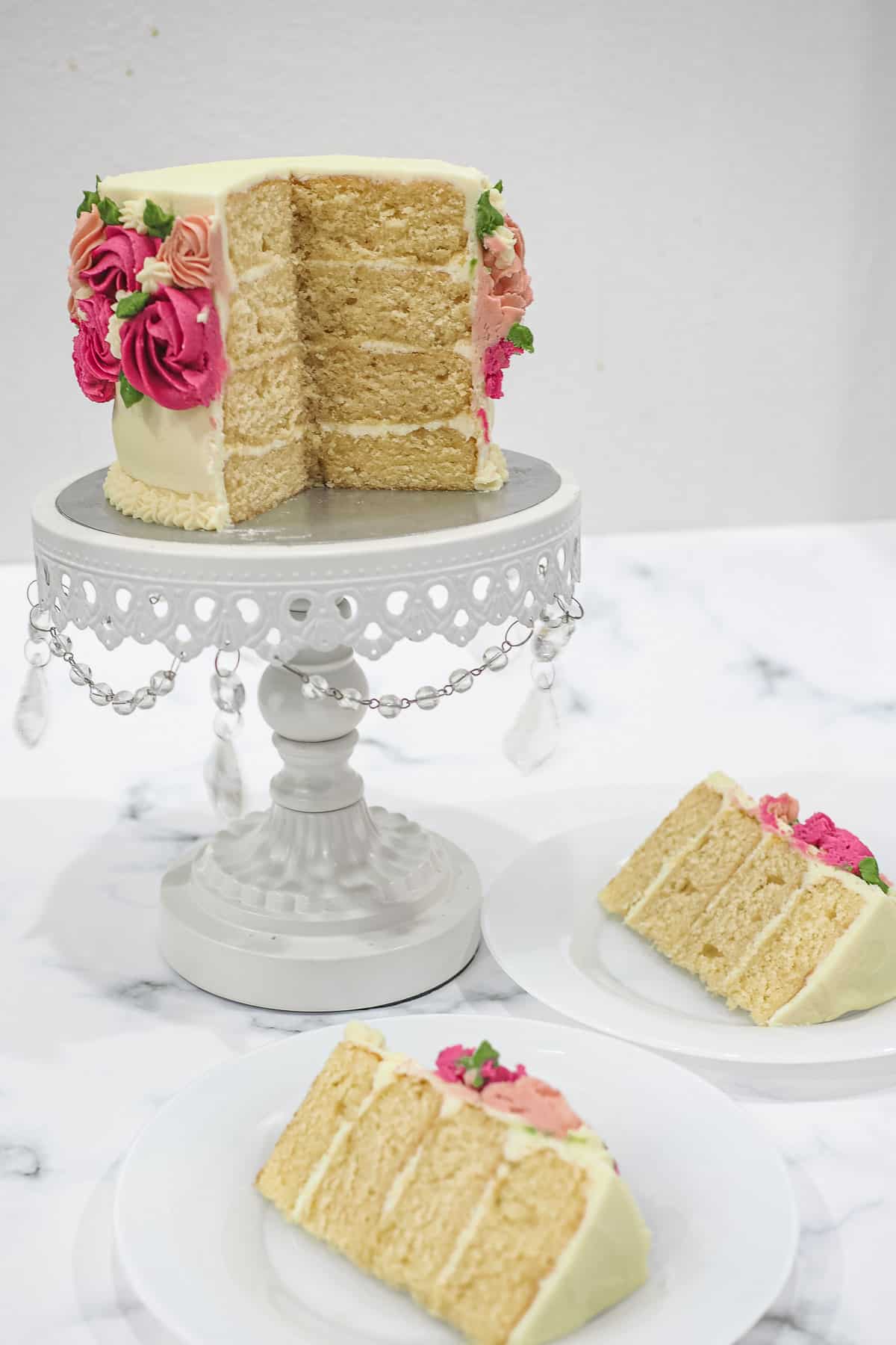 A 4 layer cake on a cake stand, with 2 slices cut out