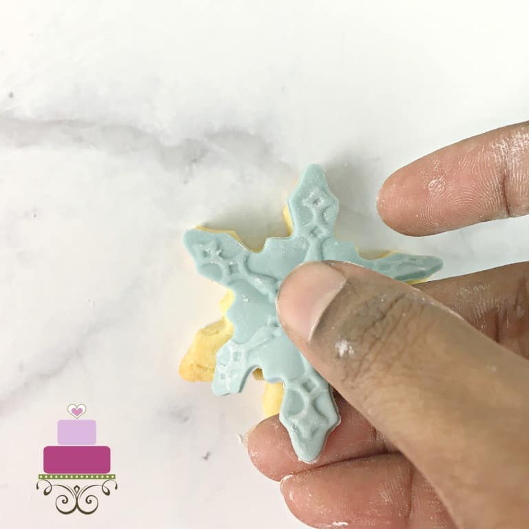 Attaching fondant cut out to a cookie