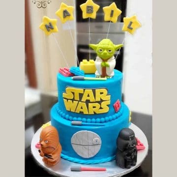 A 2 tier round cake decorated in blue. Cake is topped with figurines from Star Wars Lego.