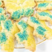 Butterfly cookies decorated with green and blue sanding sugar arranged in a plate.