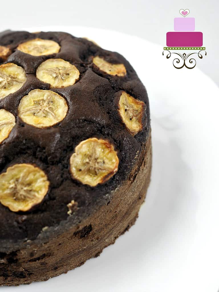 Close up view of a portion of a round chocolate cake with banana slices on top