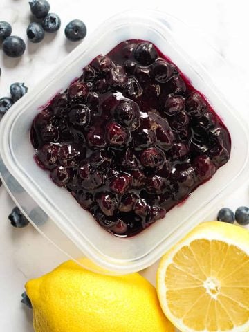 Blueberry pie filling in a square container, with lemon and fresh blueberries on the side.