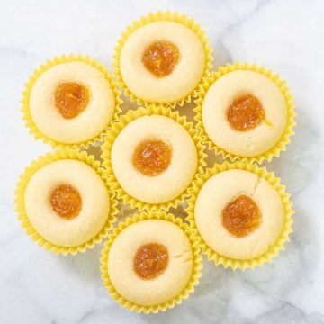 A group of mango jam filled shortbread cookies in yellow paper casings, arranged into a circle