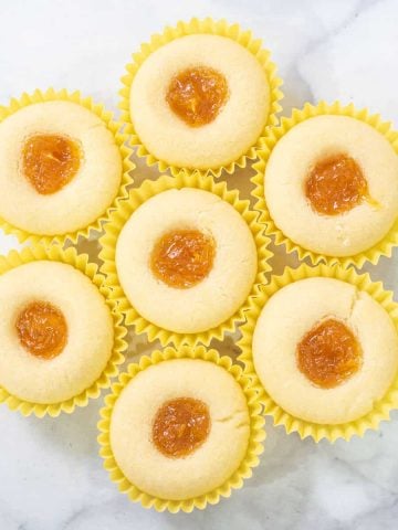 A group of mango jam filled shortbread cookies in yellow paper casings, arranged into a circle