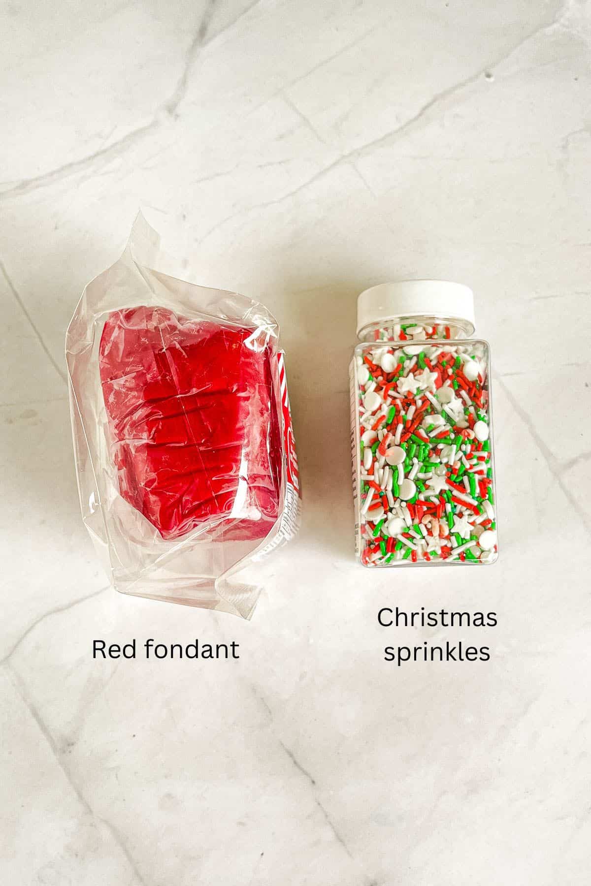 Red fondant and a bottle of red, green and white sprinkles.
