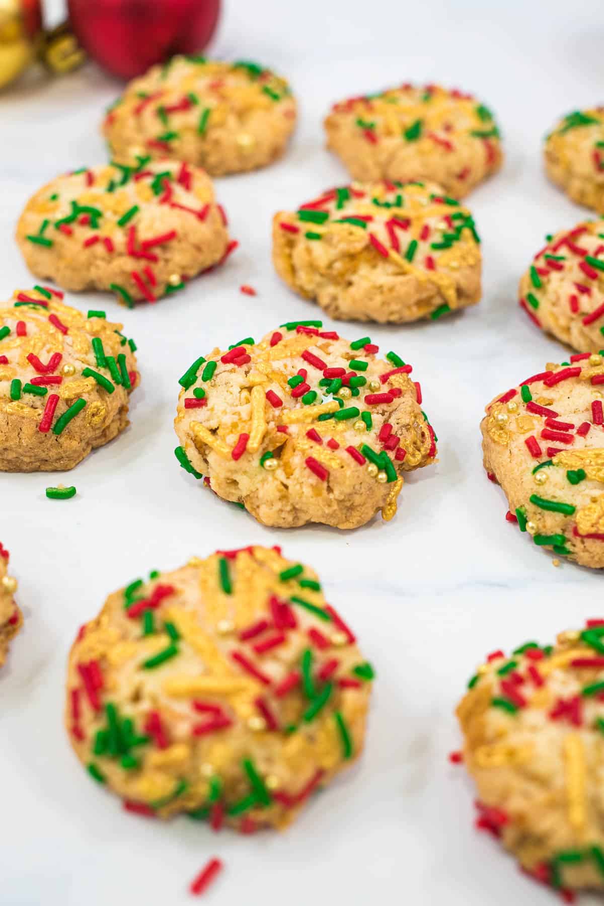 A group of cornflake cookies decorated with red, green and gold sprinkles