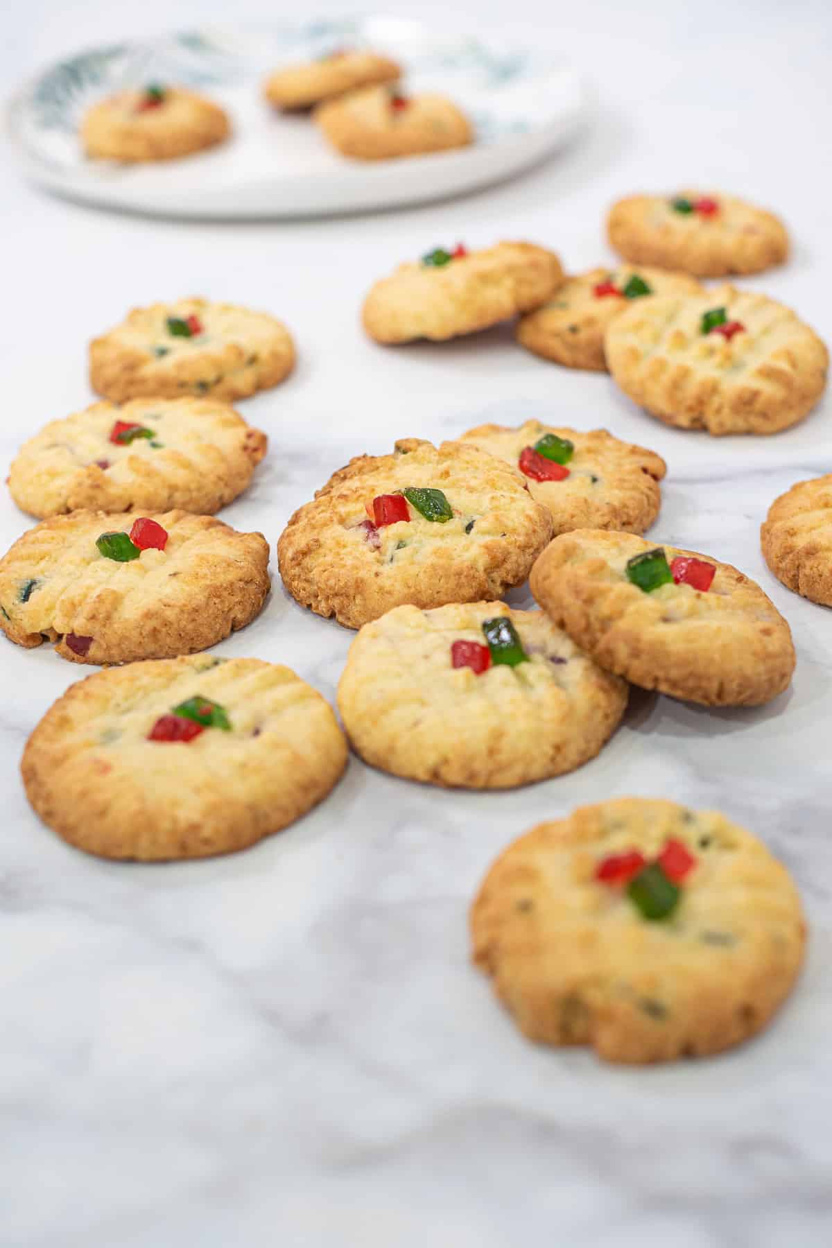 Round cookies with red and green cherry cubes topping