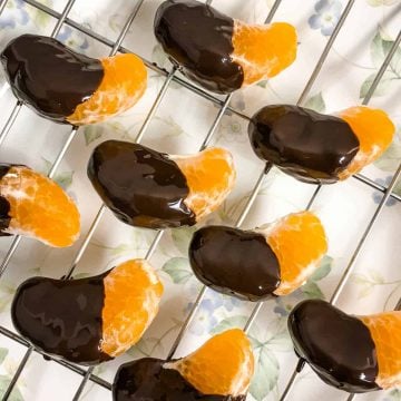 Chocolate dipped orange segments on a wire rack.